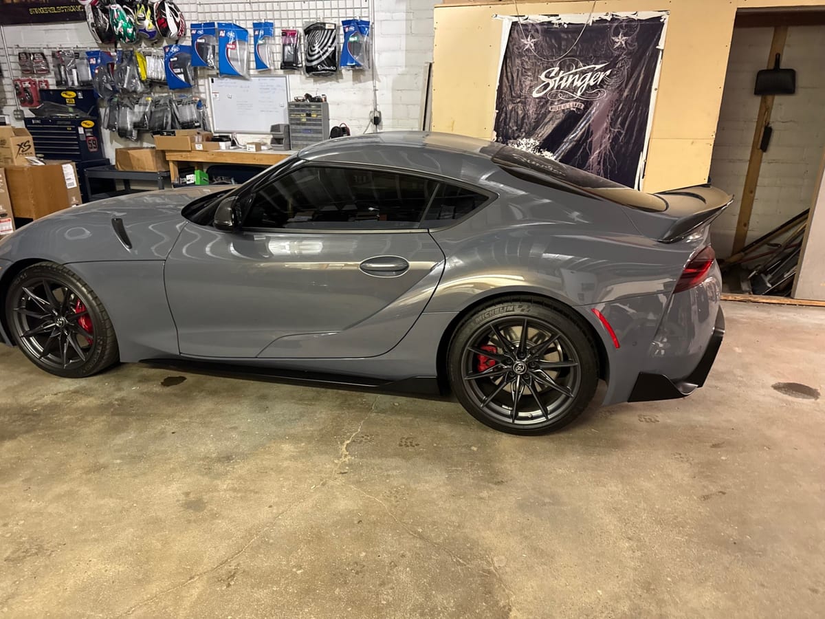 Side view of a gray coupe with tinted side glass inside a workshop.